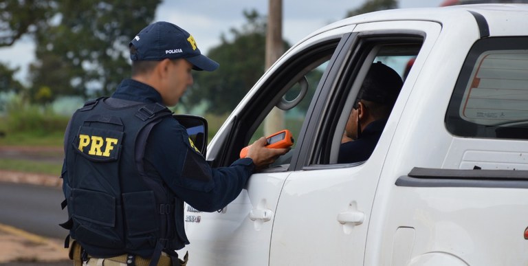 Policial rodoviário federal realizando teste do bafômetro em motorista durante blitz da Lei Seca no Brasil.